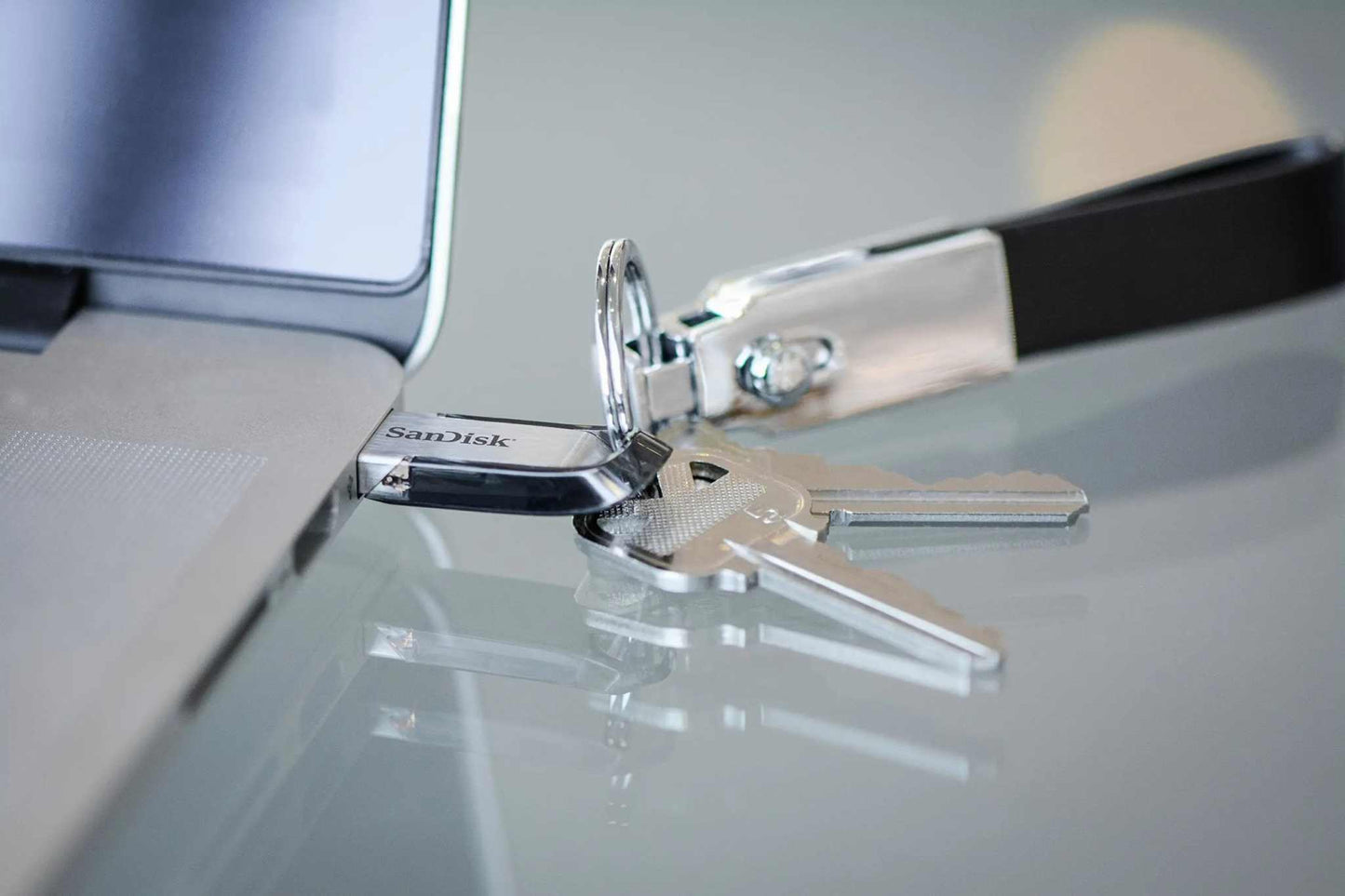 SanDisk Ultra Flair USB 3.0 Flash Drive connected to a laptop, with keys attached.